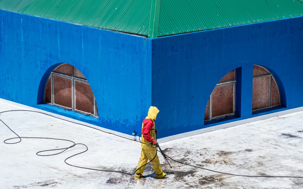 Arbeiter in Schutzkleidung führt eine professionelle Hochdruckreinigung auf einer Dachterrasse durch – RUTEK Service NRW.